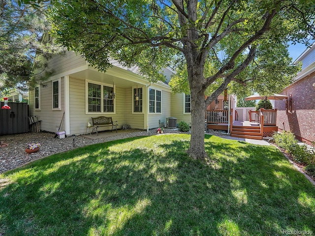 rear view of property with central air condition unit, a lawn, and a wooden deck