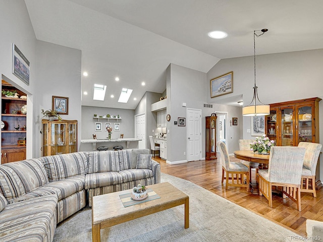 living area with visible vents, light wood-style floors, high vaulted ceiling, recessed lighting, and a skylight