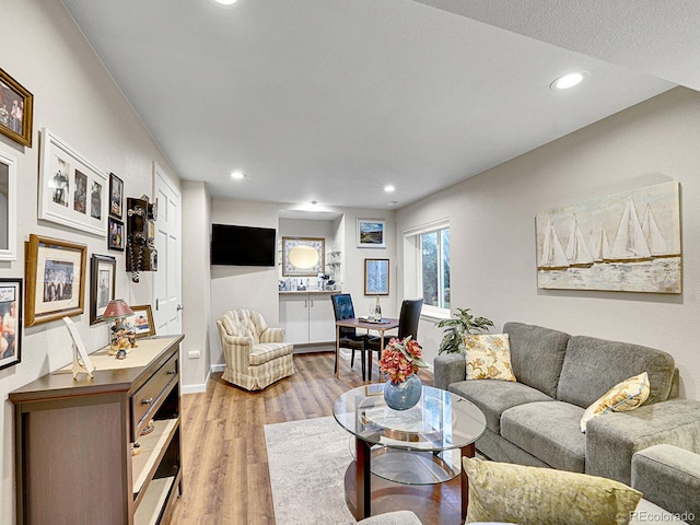 living area with recessed lighting, baseboards, and light wood-style flooring