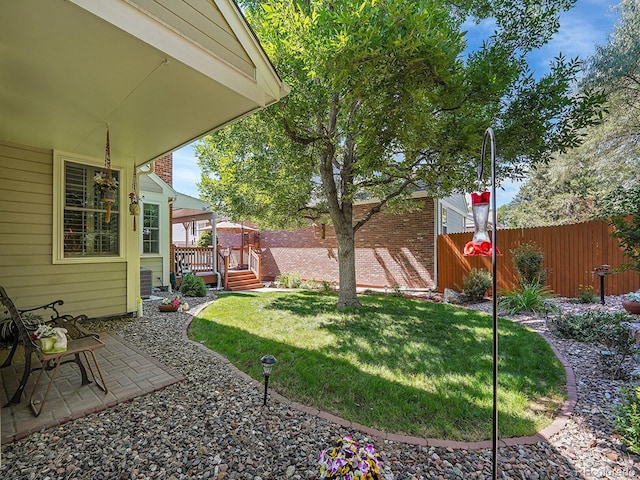 view of yard with a fenced backyard, a wooden deck, and a patio