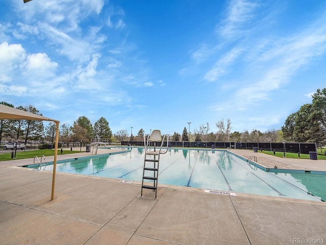 community pool with a patio area and fence