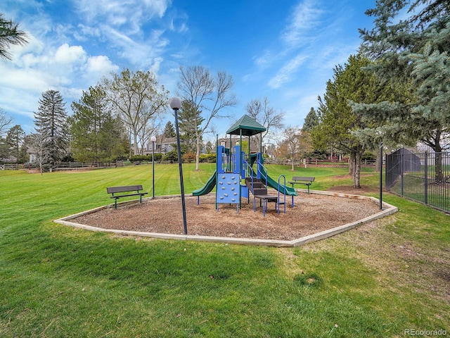 community jungle gym with a lawn and fence