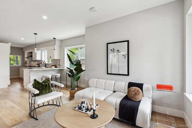 living room featuring sink, light hardwood / wood-style floors, and a healthy amount of sunlight