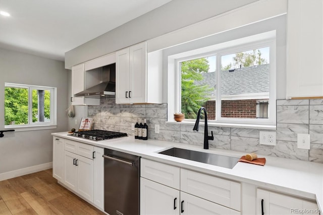 kitchen with white cabinetry, sink, wall chimney exhaust hood, stainless steel appliances, and light hardwood / wood-style flooring