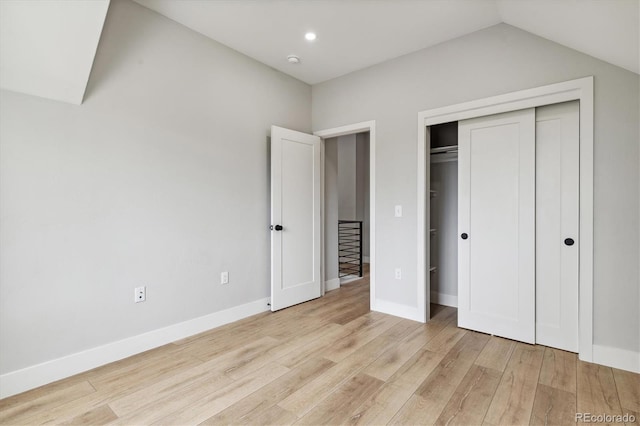 unfurnished bedroom featuring lofted ceiling, light hardwood / wood-style flooring, and a closet