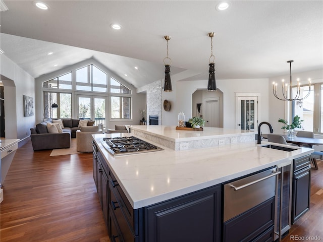 kitchen with lofted ceiling, dark hardwood / wood-style floors, sink, stainless steel gas stovetop, and a spacious island