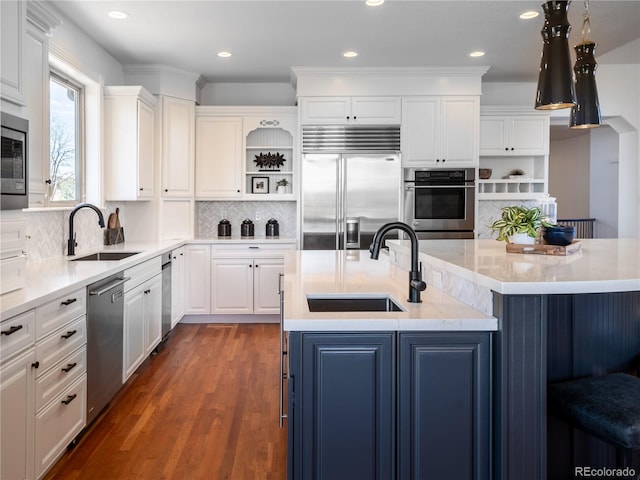 kitchen featuring a center island with sink, sink, dark hardwood / wood-style floors, built in appliances, and white cabinetry