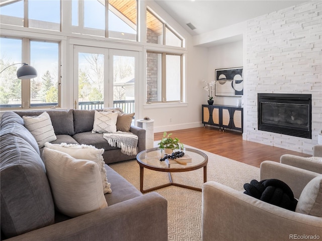 living room featuring high vaulted ceiling, a fireplace, plenty of natural light, and hardwood / wood-style floors