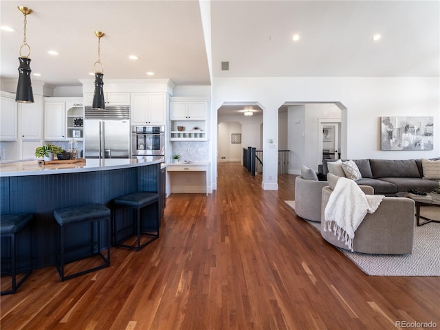 kitchen with a kitchen bar, white cabinets, stainless steel appliances, and dark wood-type flooring