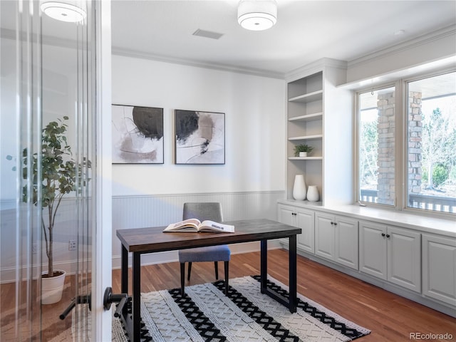 office space with built in shelves, wooden walls, light wood-type flooring, and ornamental molding