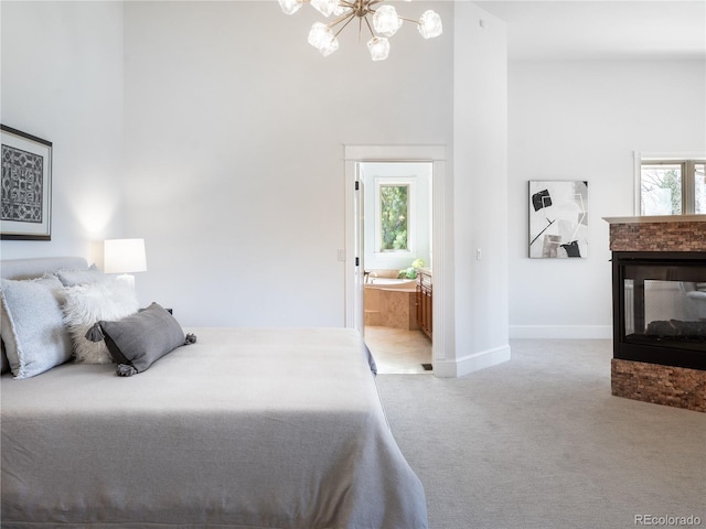 bedroom with ensuite bathroom, multiple windows, light carpet, and a multi sided fireplace