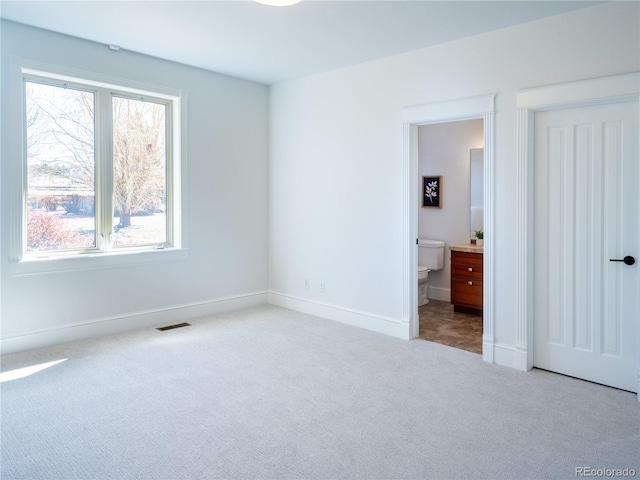 unfurnished bedroom with light carpet and connected bathroom