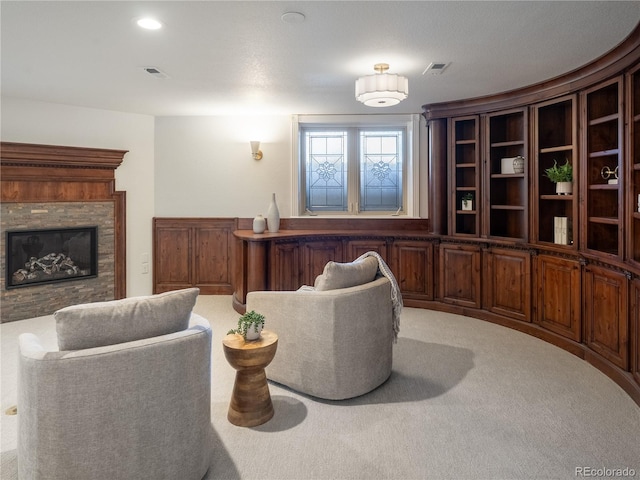 carpeted living room featuring a stone fireplace