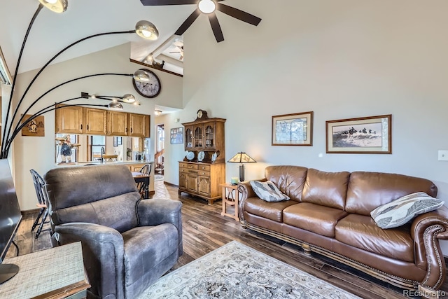 living area with baseboards, high vaulted ceiling, wood finished floors, and a ceiling fan