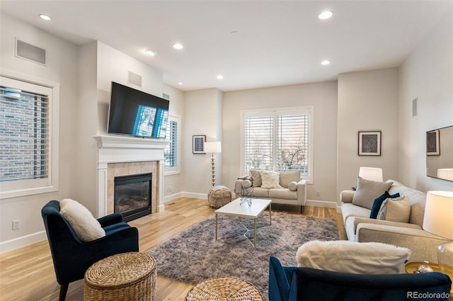 living room featuring a tile fireplace and light wood-type flooring