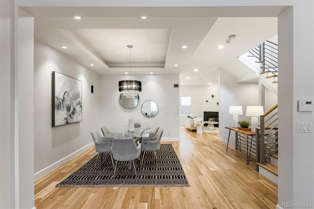 dining space featuring an inviting chandelier, a tray ceiling, and light wood-type flooring