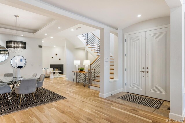 foyer with a tray ceiling, wood-type flooring, and vaulted ceiling