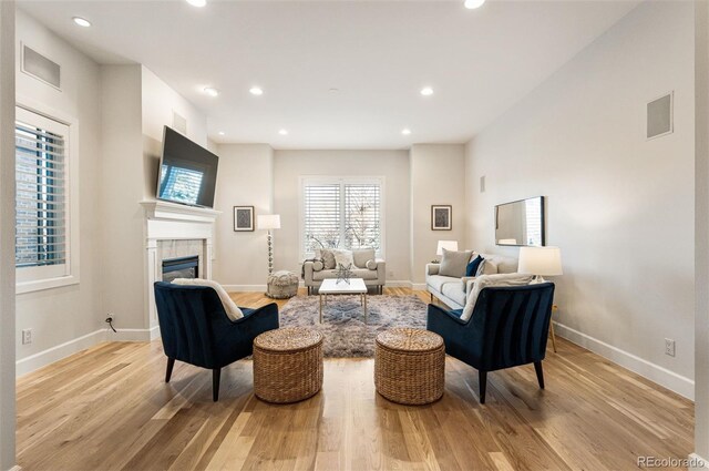 living room with a tiled fireplace and light wood-type flooring