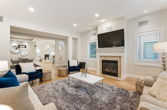 living room with a tiled fireplace and light wood-type flooring