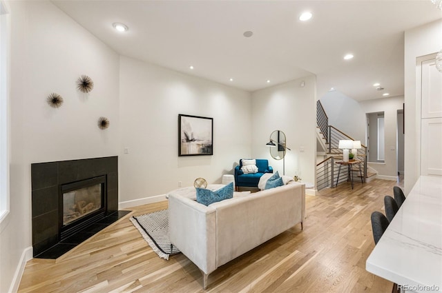 living room with a tile fireplace and light hardwood / wood-style floors