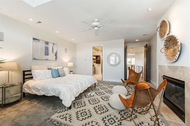 bedroom with ceiling fan, ensuite bath, and a tile fireplace