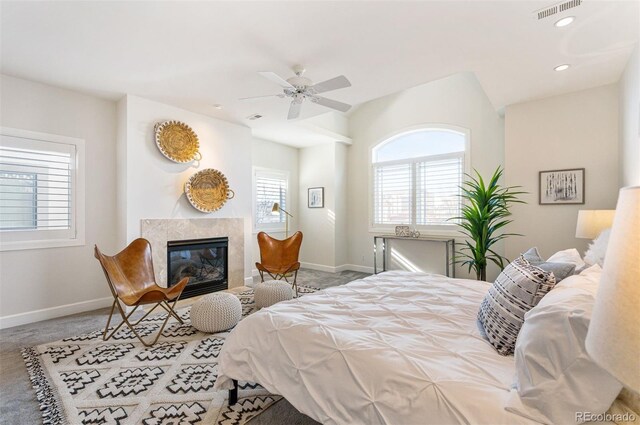 bedroom with multiple windows, a fireplace, ceiling fan, and carpet flooring