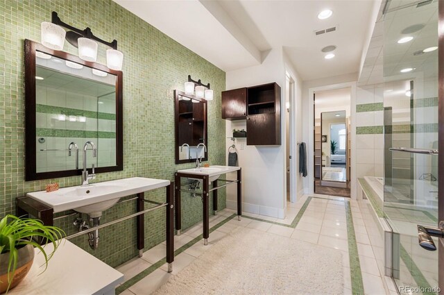 bathroom with double sink, tile walls, tile patterned floors, and walk in shower