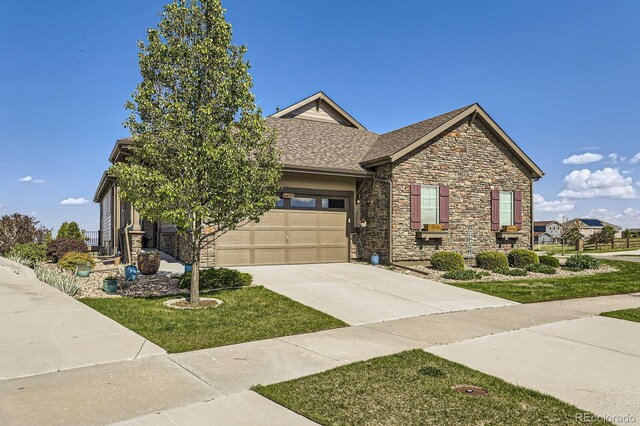 16459 W 86th Pl Unit B, Arvada, CO 80007 - view of front of home featuring stone siding, driveway, an attached garage, roof with shingles, and a front yard