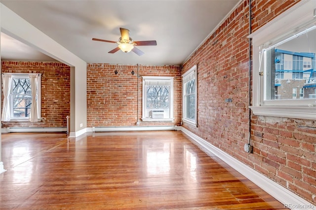 unfurnished room with baseboard heating, ceiling fan, brick wall, and light hardwood / wood-style floors