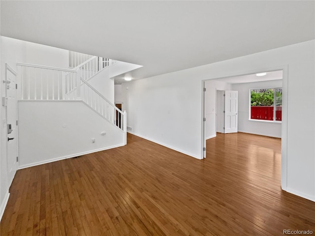 9115 W Hinsdale Pl, Littleton, CO 80128 - unfurnished living room featuring baseboards, visible vents, hardwood / wood-style flooring, and stairway