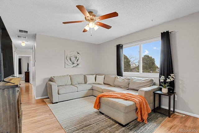 living room with wood-type flooring, a textured ceiling, and ceiling fan