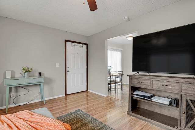 living room with ceiling fan, light hardwood / wood-style flooring, and a textured ceiling