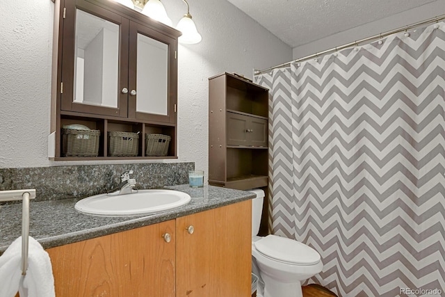 bathroom with walk in shower, vanity, a textured ceiling, and toilet