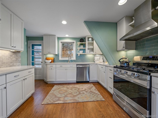 kitchen featuring light hardwood / wood-style flooring, backsplash, range hood, stainless steel appliances, and white cabinets