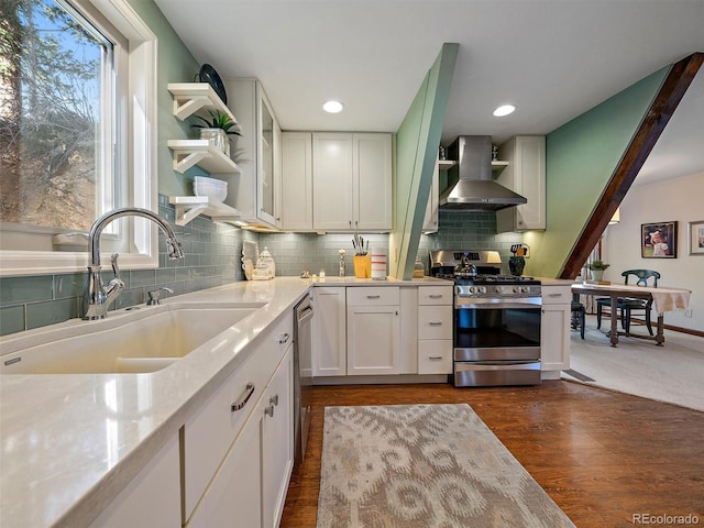 kitchen with sink, stainless steel appliances, light stone countertops, white cabinets, and wall chimney exhaust hood