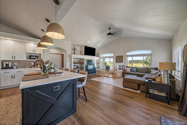 1248 Rawhide Cir, Elizabeth, CO 80107 - kitchen featuring vaulted ceiling, white cabinets, a ceiling fan, a tiled fireplace, and an island with sink