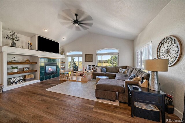 1248 Rawhide Cir, Elizabeth, CO 80107 - living room featuring ceiling fan, a tile fireplace, wood finished floors, vaulted ceiling, and built in shelves