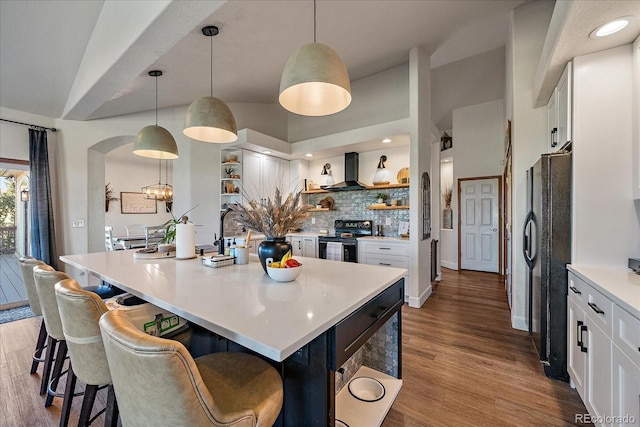 1248 Rawhide Cir, Elizabeth, CO 80107 - kitchen featuring open shelves, black appliances, wall chimney exhaust hood, a kitchen bar, and white cabinets