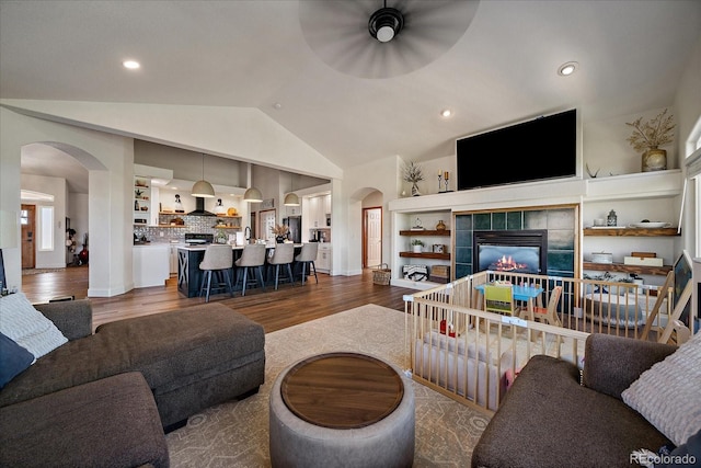1248 Rawhide Cir, Elizabeth, CO 80107 - living area with arched walkways, dark wood finished floors, a ceiling fan, vaulted ceiling, and a tiled fireplace