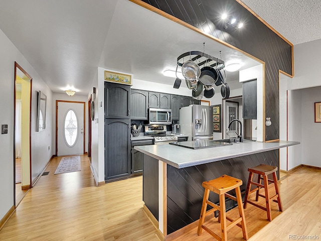 kitchen with a breakfast bar area, light countertops, appliances with stainless steel finishes, a sink, and a peninsula