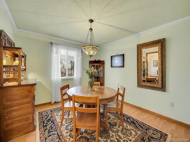 dining room with crown molding, a textured ceiling, baseboards, and wood finished floors