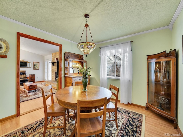 dining space with a textured ceiling, ornamental molding, light wood-type flooring, and a wealth of natural light