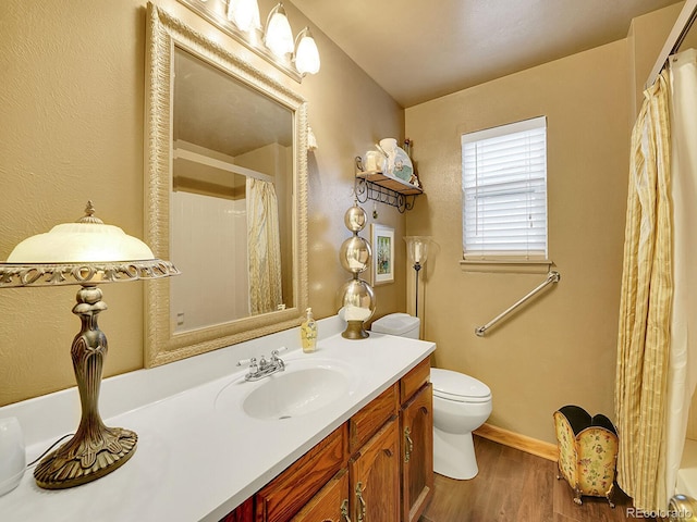 bathroom with a shower with shower curtain, toilet, vanity, wood finished floors, and baseboards