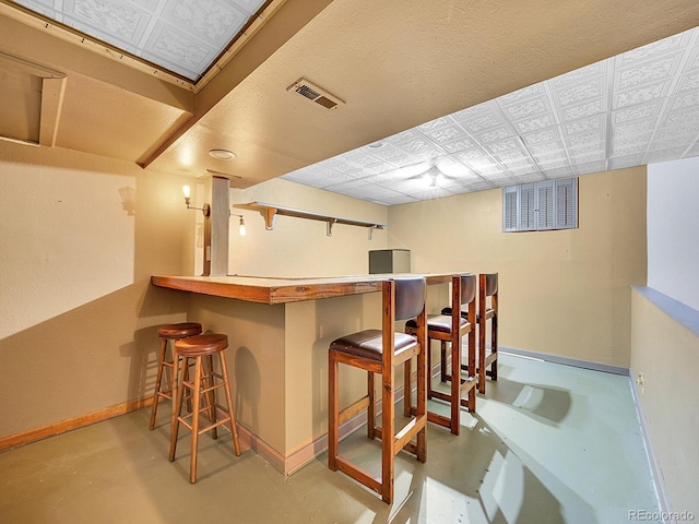 bar with visible vents, a bar, baseboards, and finished concrete flooring