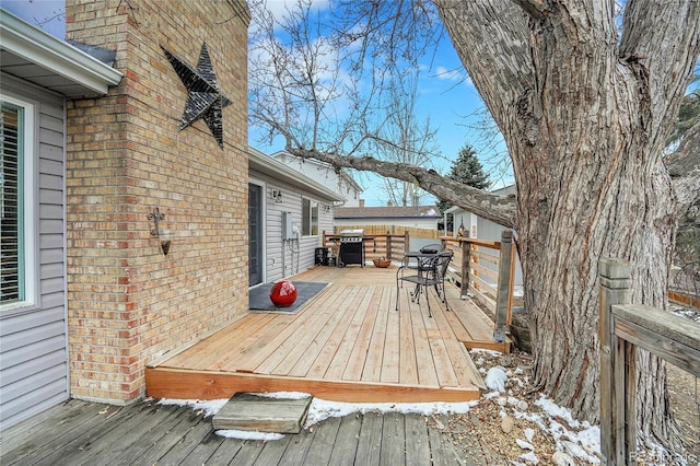 snow covered deck with outdoor dining space and a grill