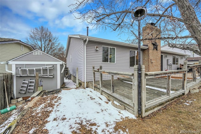 snow covered back of property featuring a deck and a chimney