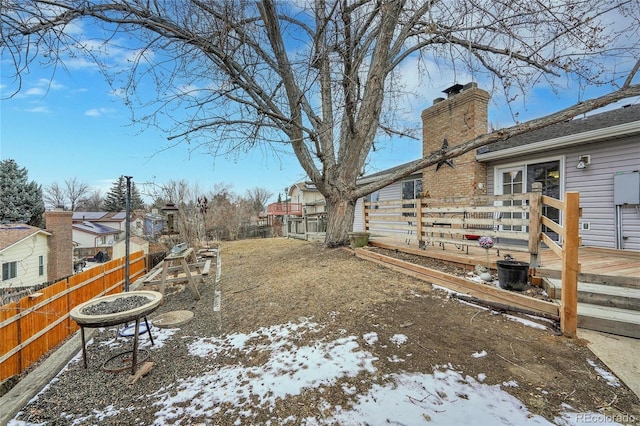 yard layered in snow with a deck, a fire pit, and a fenced backyard