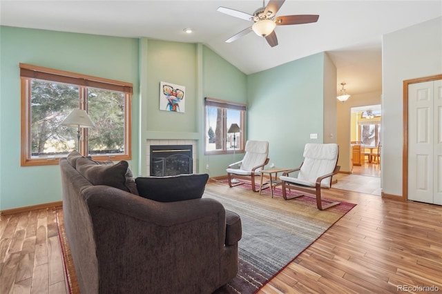 living room with vaulted ceiling, ceiling fan, a fireplace, and wood-type flooring