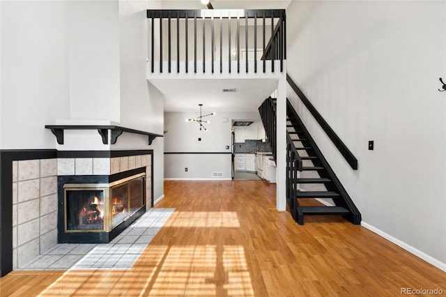 1885 S Quebec Way Unit A28, Denver, CO 80231 - unfurnished living room with wood finished floors, a tile fireplace, baseboards, stairway, and a high ceiling