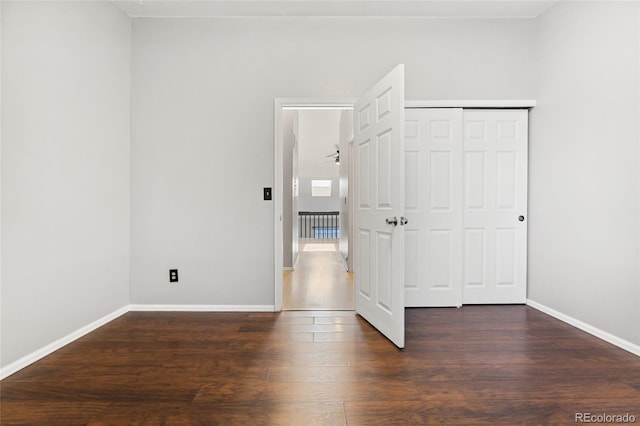 1885 S Quebec Way Unit A28, Denver, CO 80231 - unfurnished bedroom featuring dark wood-style flooring, baseboards, and a closet